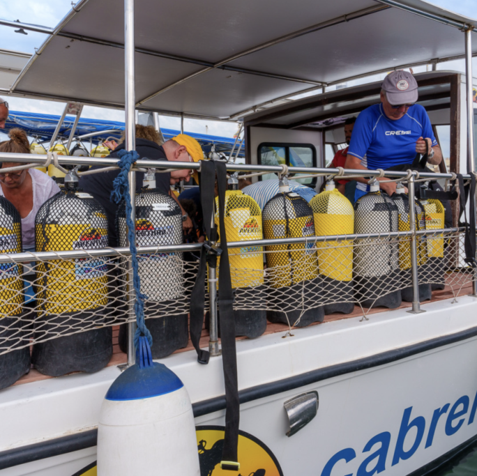 Grupo de buceadores en un barco revisando equipos de presión.