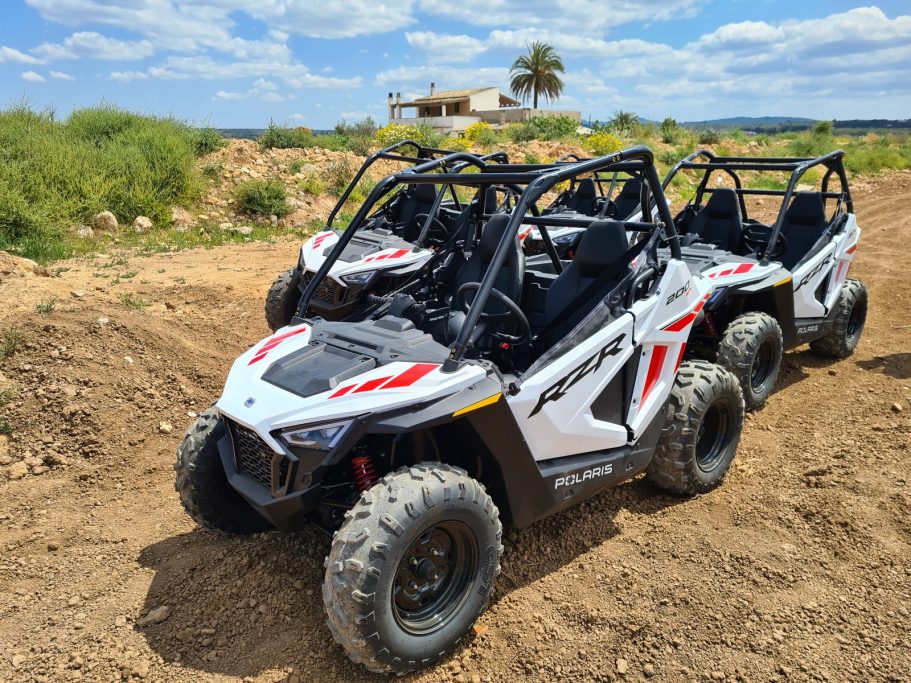 Dos vehículos todoterreno en un terreno arenoso bajo un cielo despejado.